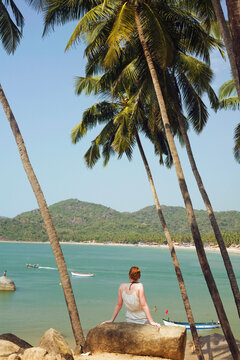 Mid adult woman sitting on a rock, Palolem Beach, Goa, India