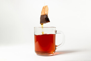 A brewed tea bag in a transparent glass on a white background. A quick way to prepare tea. used tea bag