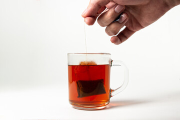 A brewed tea bag in a transparent glass on a white background. A quick way to prepare tea. used tea bag