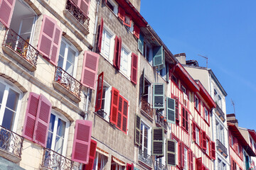 Fototapeta na wymiar Classical colourful facades in Bayonne, french part of Basque Country, France. Different windows and balconies with shutters of faded colours