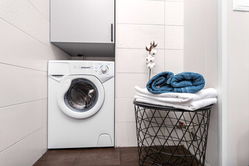 A washing machine built into a niche under the cabinet in a bright bathroom with a table with...