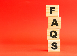 Wooden cubes with word FAQS. Wooden cubes on a red background. Free space on the left.