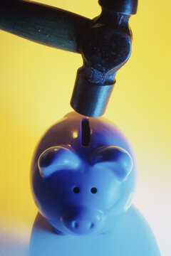 Close-up of a hammer over a piggy bank