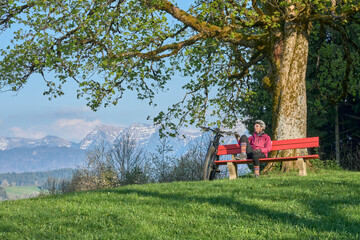 pretty senior woman having a break during a mountain bike tour  in  springtime in the Allgau...