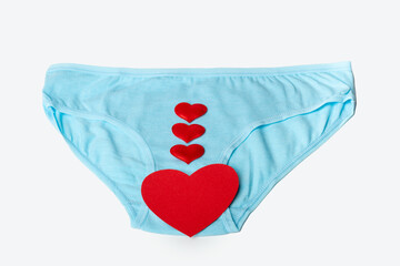 Blue women's panties and red hearts as a symbol of women's health on a white background. Women's health concept.