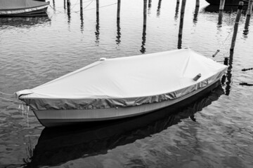 Covered and roped boat in the water in black and white