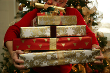 Close-up of a person carrying a pile of Christmas presents