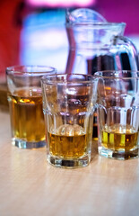 Three glasses of drinks with jug on table in a bar close up