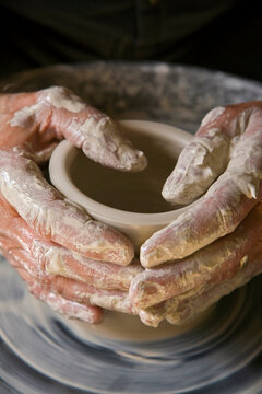 Person's hands making pottery