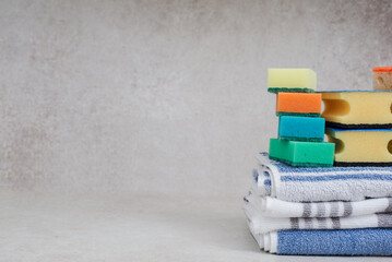 various sponges for washing dishes and kitchen towels on a gray background.