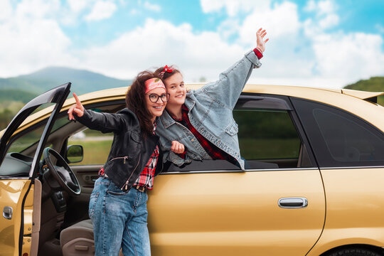 Automobile's trip. Happy mother and daughter pose with the car and rejoice in getting a driver's license. The concept of buying a new car