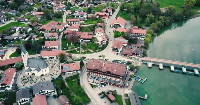 4k aerial of rural german town seebruck in bavaria with church, bridge, harbour surrounded by blue lake
