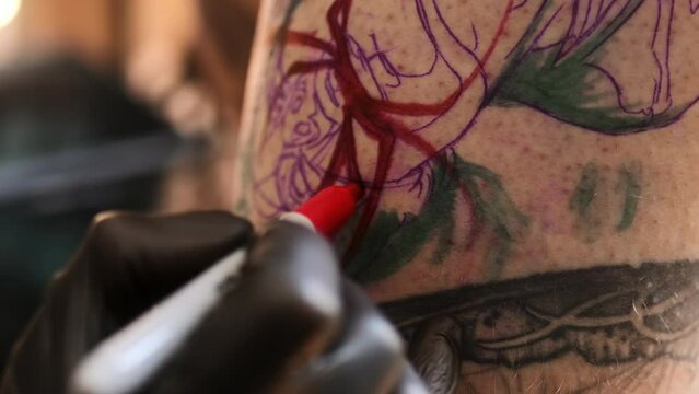 Tattoo artist drawing and makes a sketch on the client's skin marking for a tattoo with a marker