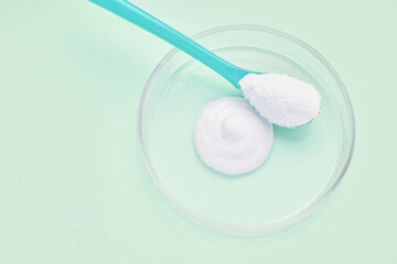 Collagen white powder. Pastel color background. Health product. Woman cosmetics concept. Sport supplement. Skincare cosmetics. Green monochrome. Cream smear. Spoon