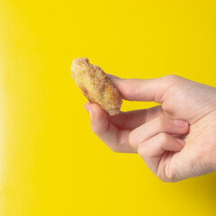 Holding a fried snack chicken nuggets on an yellow background in your hand