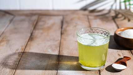 Collagen powder and glass of water on wooden background.
