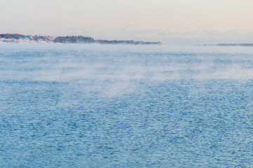 Minimal view of the sea from Helsinki coastline. The weather is so cold that the water freezes and crates a light mist on its surface