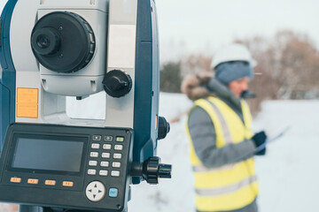 cadastral works with an electronic total station, a female engineer in the background out of focus,...