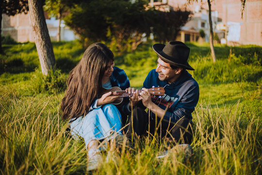 Mujer aprendiendo a tocar Ukulele o guitarra al aire libre. Concepto de educaci&oacute;n, m&uacute;sica y personas.