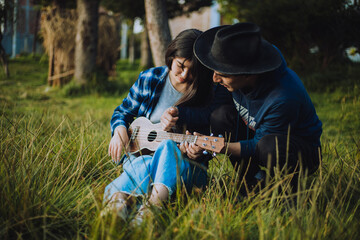 Mujer aprendiendo a tocar Ukulele o guitarra al aire libre. Concepto de educación, música y personas.