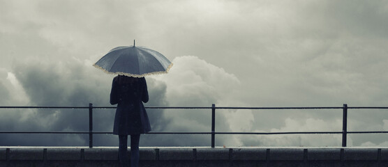 Woman with umbrella standing on the rain during autumn storm  - obrazy, fototapety, plakaty