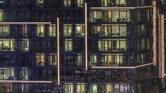 Flat night panorama of multicolor light in windows of multistory buildings aerial timelapse.