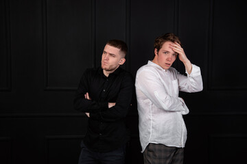 Beautiful pair of male students in white shirts talking to each other. Black background.