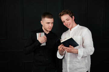 Beautiful pair of male students in white shirts talking to each other. Black background.