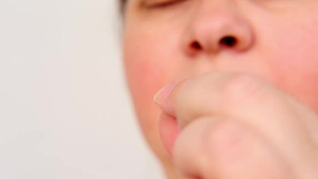 close-up of mature charismatic woman 50 years puts in his mouth and swallows a brown pill, concept most important element for life, human health, quench thirst, drug therapy