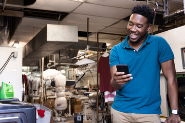 Man working in a dry cleaners taking a break in back room, using phone