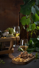 White wine in glasses, pear, cheese plate and grapes.