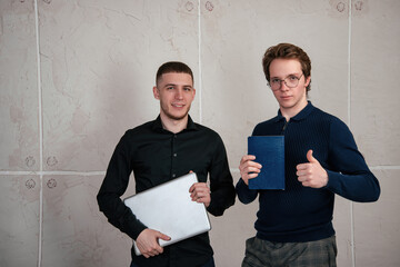 Young couple of male students studying remotely using a laptop. Background white loft.