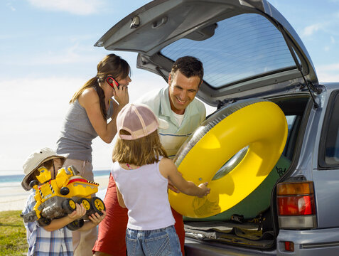 Young family unpacking car for a day at the beach