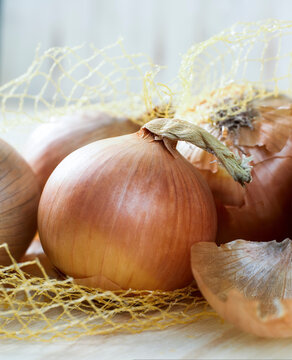 Close up of onions in opened net bag resting on wooden board