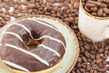 Donut with chocolate glaze, coffee beans, cup of coffee beans, macro, copy space