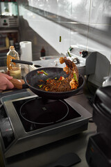 Chef hand keep wok. Closeup hands tossing food at professional dark kitchen. Chef in prepare asian food.