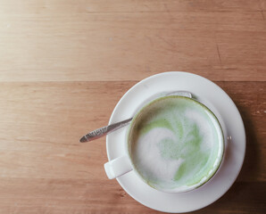 Top view hot green tea latte on wooden table background in the afternoon, light effect 