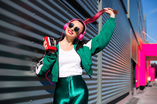 Back in time 90s 80s. Stylish girl in retro jacket and vintage cassette player listens to music, fashion trends, entertainment, heat in summer