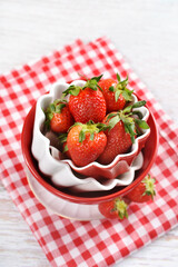Red and white bowls with fresh strawberries top view