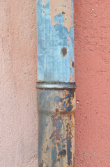 Close Up of Old Metal Rainwater Pipe against Pink Painted Cement Wall