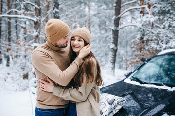 Obraz premium winter love story. couple in love in the winter forest hugging. woman and man in beige clothes