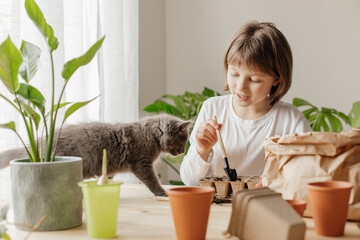 The girl is planting seeds for seedlings at home. Hobby for children and parents. Little helpers