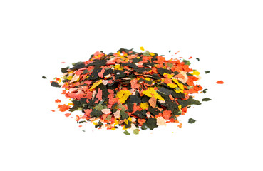 Dry multi-colored compound fishfeed flakes on White background. Side view