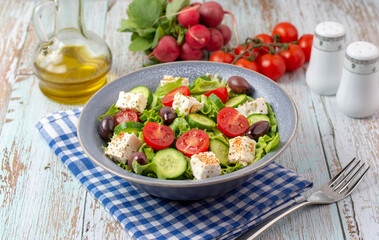 Fresh Gree salad from green leaves mix, vegetables, cheese, spices, olive oil and balsamic. Spring salad, healthy concept.  Wooden background