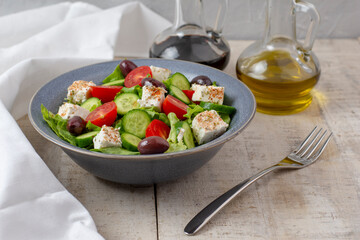Fresh vegan salad from green leaves mix, vegetables, cheese, spices, olive oil and balsamic. Spring salad, healthy concept.  Wooden background