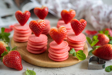 Romantic breakfast for lovers. Small pancakes with strawberries. Pink pancakes with hearts. Close-up.
