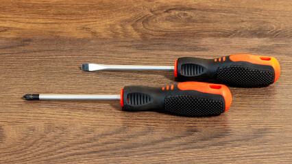 Two screwdrivers with different shaped tips on a wooden surface