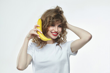 attractive girl holds a banana in her hands and pretends to call through it