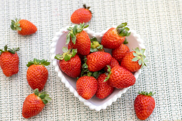 Delicious ripe fresh strawberries in a white bowl on a wooden table background