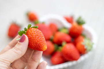 Delicious ripe fresh strawberries in a white bowl on a wooden table background